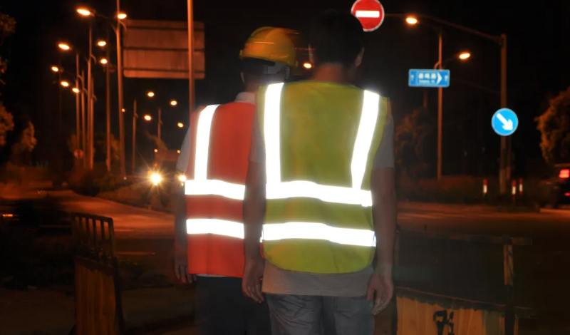 Effect of man wearing safety vest standing in front of headlights